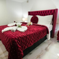 Luxurious bedroom with a plush red velvet bed and ambient lighting at Villa Virginia in Kalamaki.