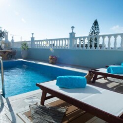 Private swimming pool with two sun loungers and rolled turquoise towels at Villa Virginia in Kalamaki.